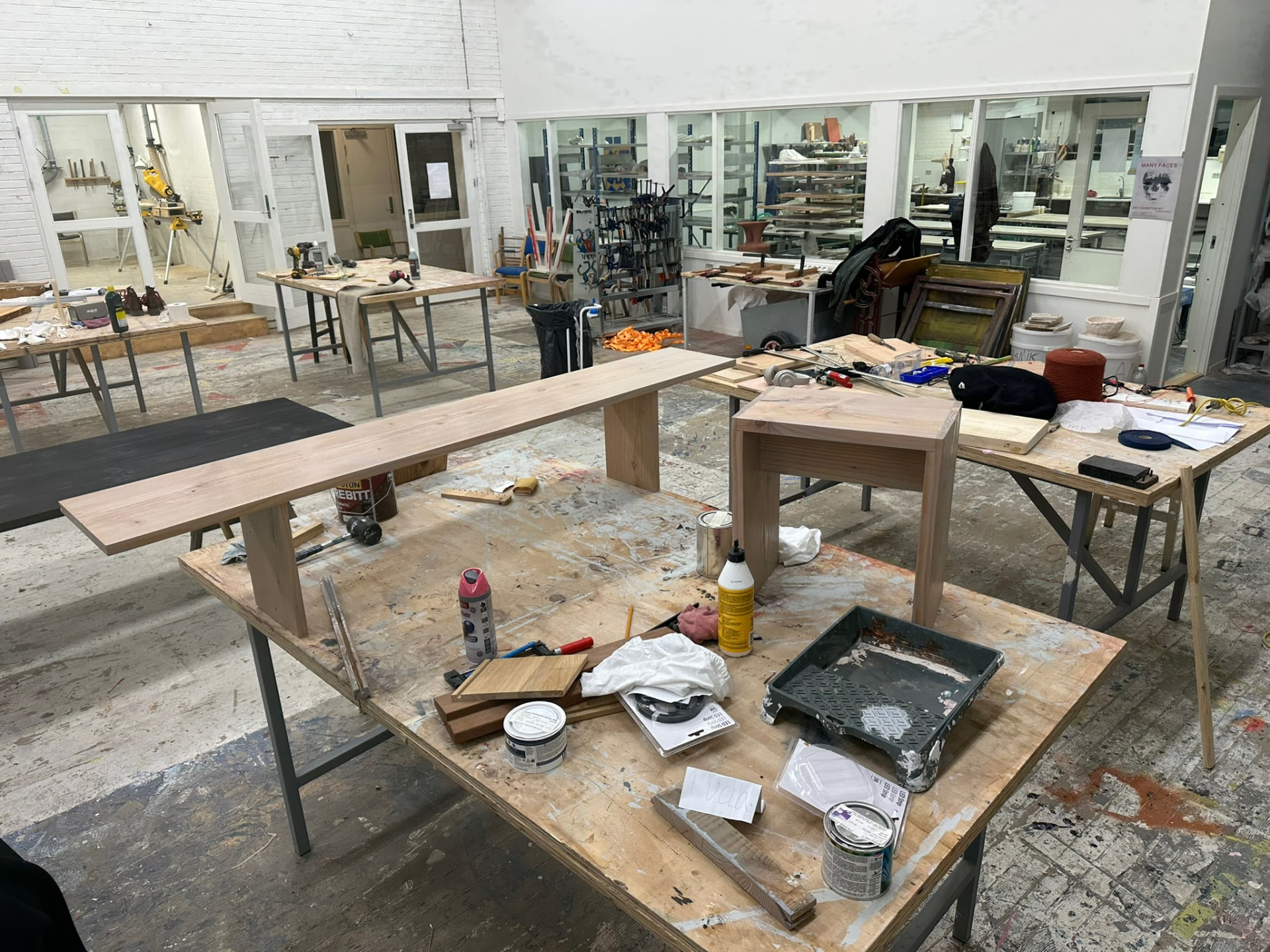 Workshop space with a long wooden table in progress, tools and materials spread across the benches.